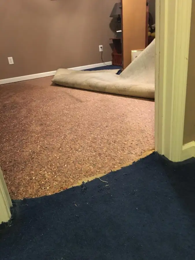 Carpet pad removal revealing water damage during Water Mitigation Services in Pensacola Station